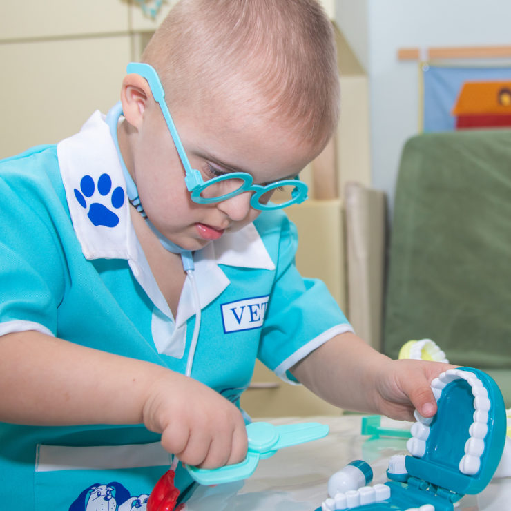 A boy with Down syndrome plays a role-playing game with dental toys and model