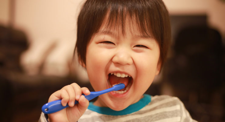 Image of child brushing his teeth and smiling