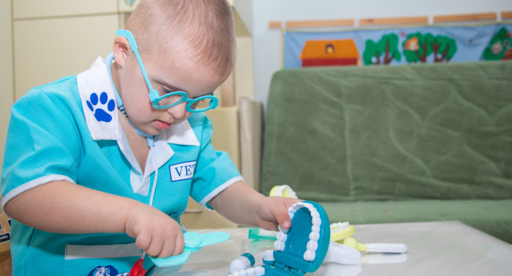 A boy with Down syndrome plays a role-playing game with dental toys and model