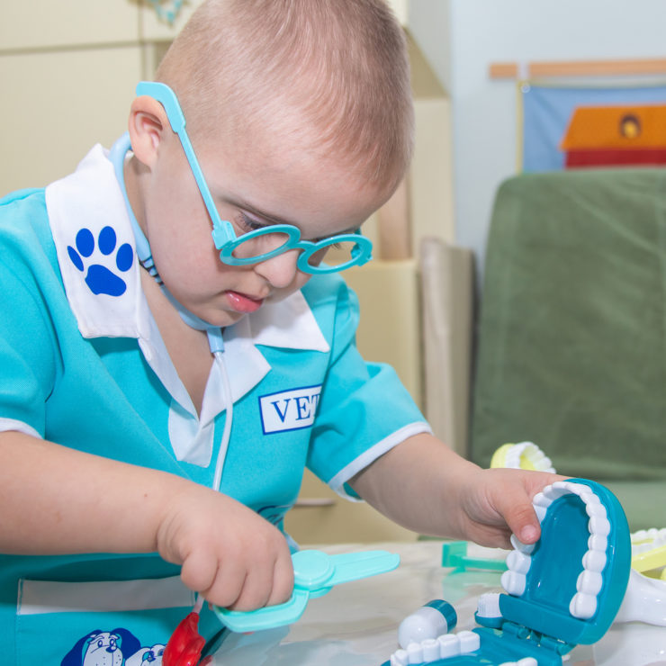 A boy with Down syndrome plays a role-playing game with dental toys and model