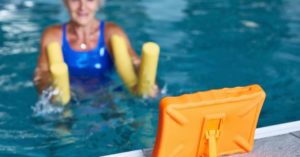 Lady in swimming pool using a tablet showing her workout as part of the Good Boost program at Hutton Moor leisure centre