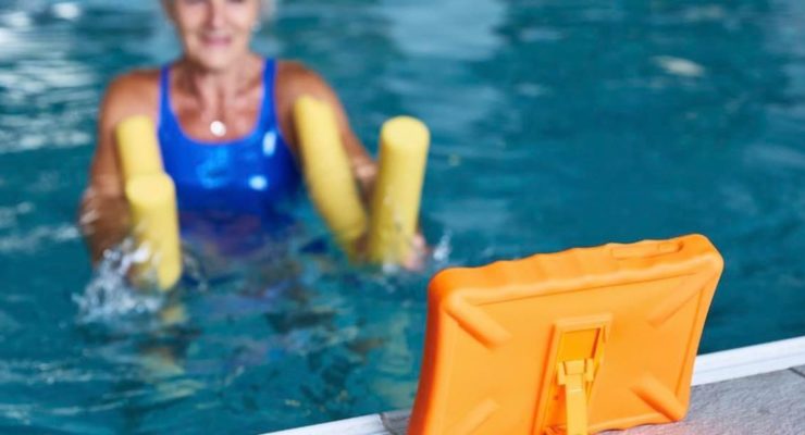 Lady in swimming pool using a tablet showing her workout as part of the Good Boost program at Hutton Moor leisure centre