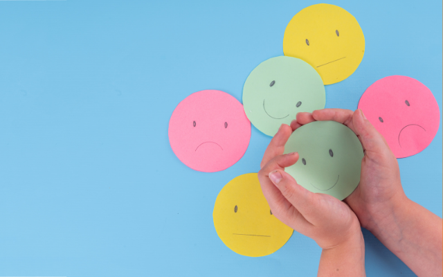 Hands holding paper smiley and sad faces
