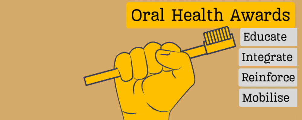 Golden fist holds golden toothbrush with title "Oral Health Awards" and the award stands "Educate, Integrate, Reinforce and Mobilise" listed on plaques.