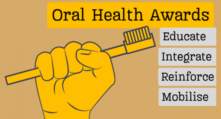 Golden fist holds golden toothbrush with title "Oral Health Awards" and the award stands "Educate, Integrate, Reinforce and Mobilise" listed on plaques.