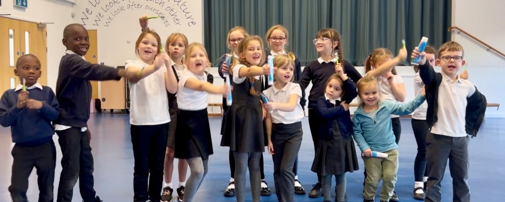 Children showing their toothbrushes and toothpastes