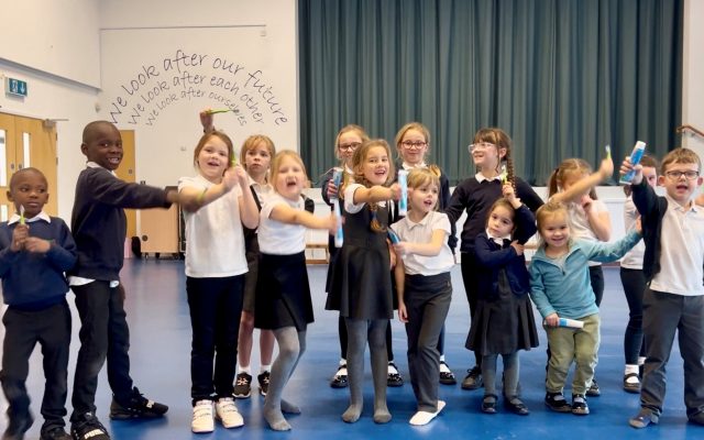 Children showing their toothbrushes and toothpastes