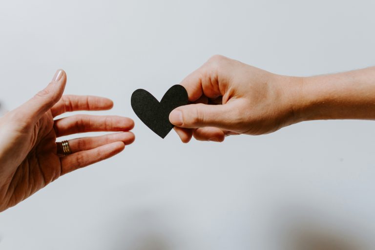 Two hands holding a black heart